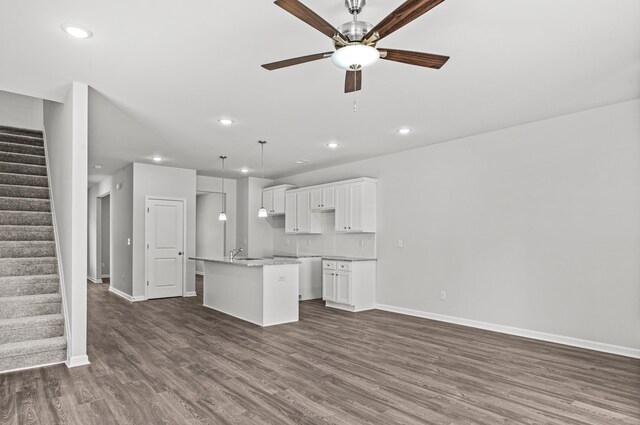 kitchen with pendant lighting, ceiling fan, white cabinetry, an island with sink, and dark hardwood / wood-style flooring