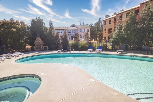 view of swimming pool with a patio, an outdoor stone fireplace, and a community hot tub