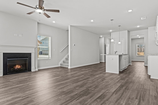 unfurnished living room with dark wood-type flooring and ceiling fan