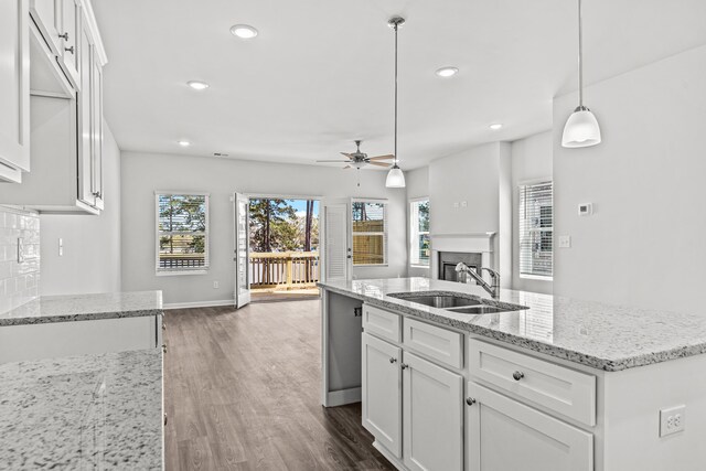 kitchen featuring pendant lighting, an island with sink, sink, white cabinets, and dark hardwood / wood-style flooring