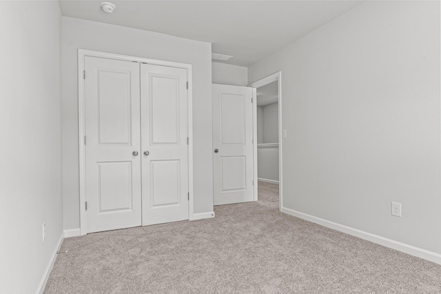 unfurnished bedroom with light colored carpet and a closet