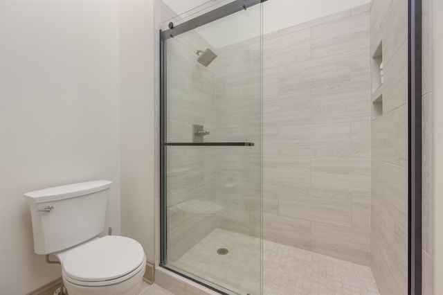 bathroom featuring a shower with door and toilet