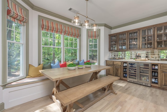 dining area with crown molding, breakfast area, and light hardwood / wood-style flooring