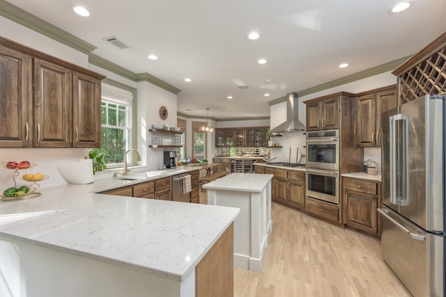 kitchen featuring sink, a center island, kitchen peninsula, stainless steel appliances, and wall chimney range hood