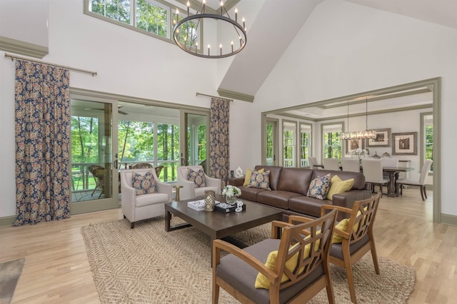 living room with a notable chandelier, a towering ceiling, and light hardwood / wood-style flooring