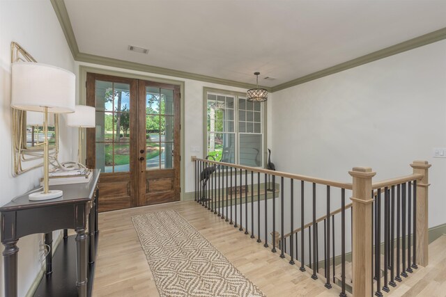 entryway with ornamental molding, light wood-type flooring, and french doors