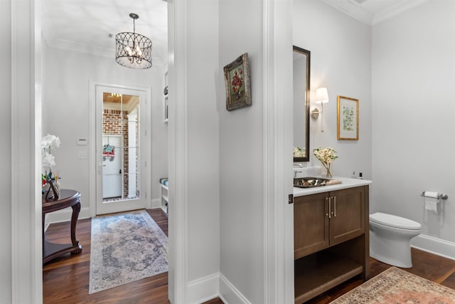 foyer entrance with sink, crown molding, a notable chandelier, and dark hardwood / wood-style floors