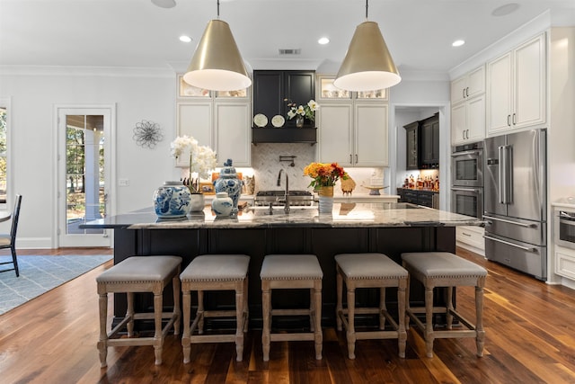 kitchen with a kitchen island with sink, decorative light fixtures, and stainless steel appliances