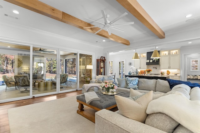 living room featuring crown molding, beam ceiling, light hardwood / wood-style flooring, and ceiling fan