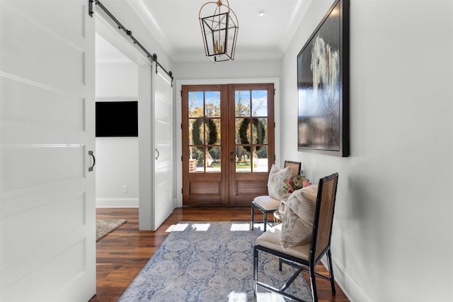 foyer entrance with a barn door, a notable chandelier, dark hardwood / wood-style flooring, and french doors