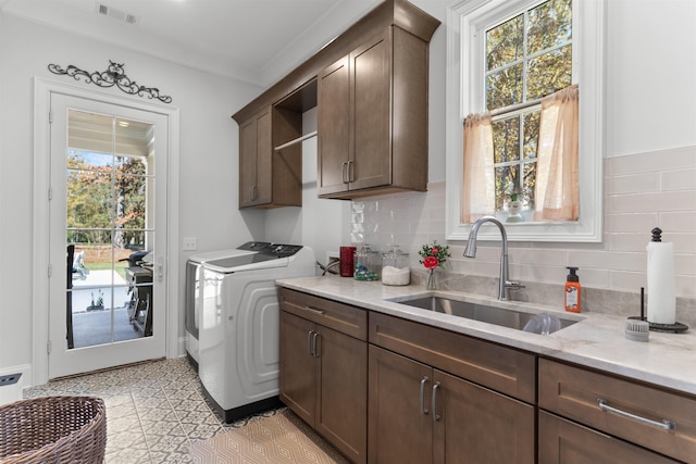 laundry room featuring sink, crown molding, washer and clothes dryer, and cabinets