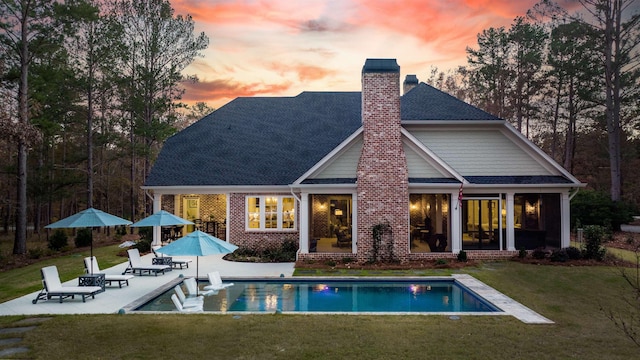 back house at dusk with a yard and a patio