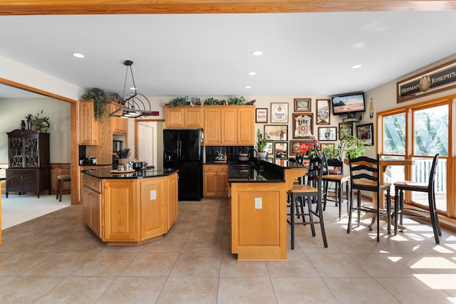 kitchen with sink, a kitchen bar, hanging light fixtures, a center island, and black fridge with ice dispenser