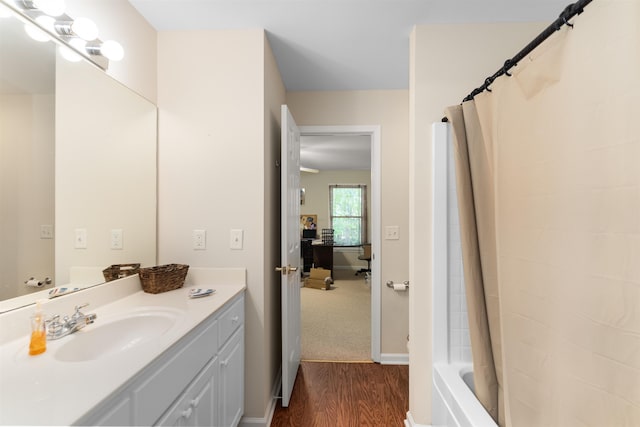 bathroom with hardwood / wood-style flooring, vanity, and shower / tub combo with curtain