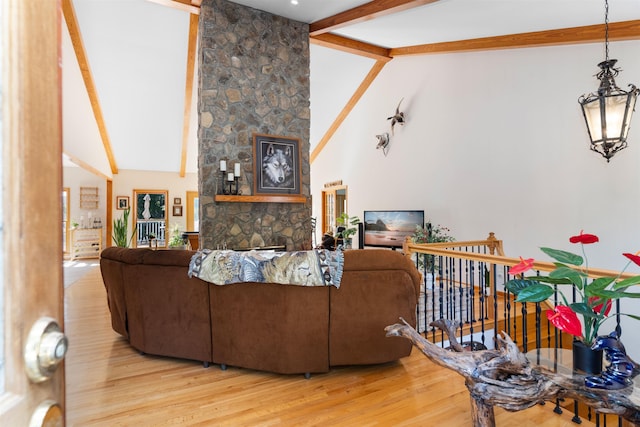 living room with a stone fireplace, an inviting chandelier, high vaulted ceiling, hardwood / wood-style flooring, and beamed ceiling