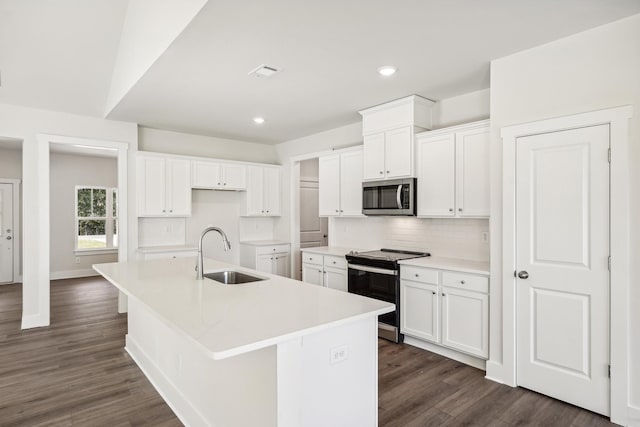 kitchen with electric stove, sink, tasteful backsplash, white cabinets, and a center island with sink