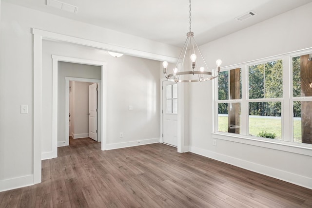 unfurnished dining area featuring an inviting chandelier and hardwood / wood-style flooring