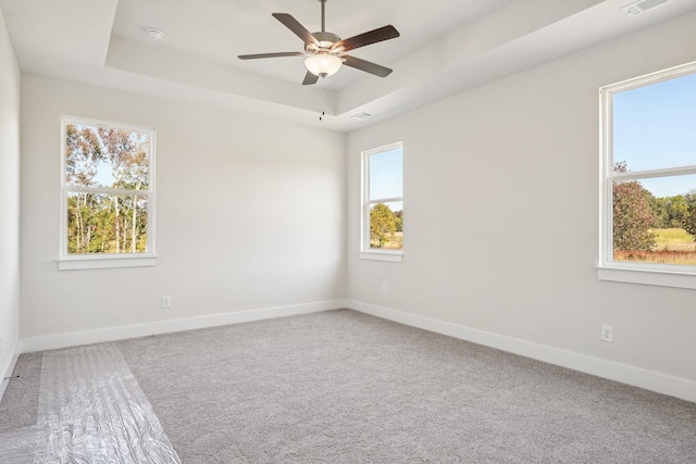 unfurnished room with ceiling fan, a tray ceiling, and carpet