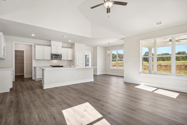 kitchen with sink, hanging light fixtures, tasteful backsplash, white cabinets, and a center island with sink