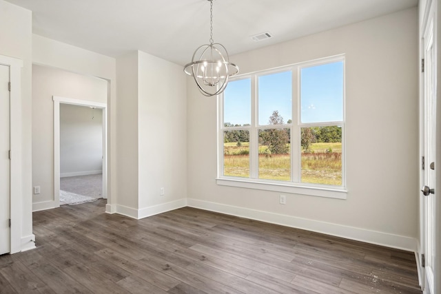 unfurnished dining area with dark wood-type flooring and a notable chandelier