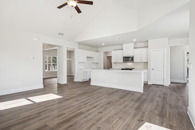 kitchen featuring white cabinetry, sink, high vaulted ceiling, and a center island with sink