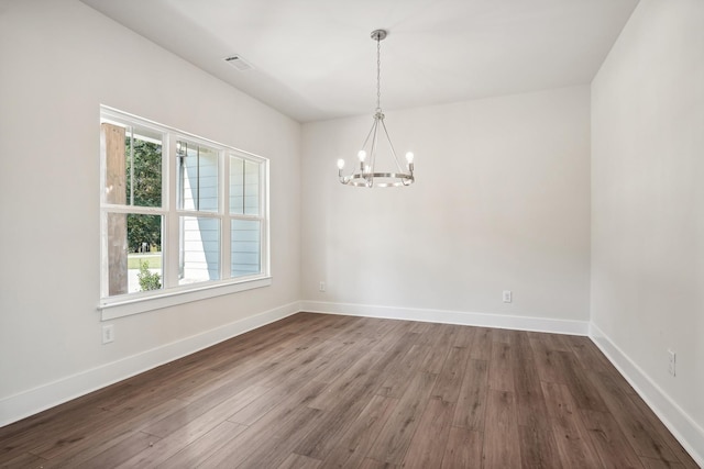 spare room featuring dark hardwood / wood-style floors and an inviting chandelier