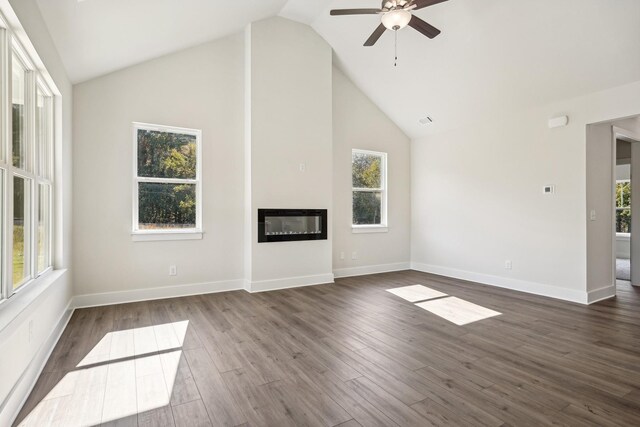 unfurnished living room featuring dark wood-type flooring, ceiling fan, plenty of natural light, and high vaulted ceiling