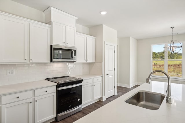 kitchen with sink, white cabinets, pendant lighting, stainless steel appliances, and backsplash