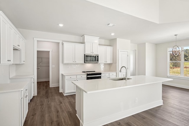 kitchen with range with electric stovetop, tasteful backsplash, an island with sink, sink, and white cabinets