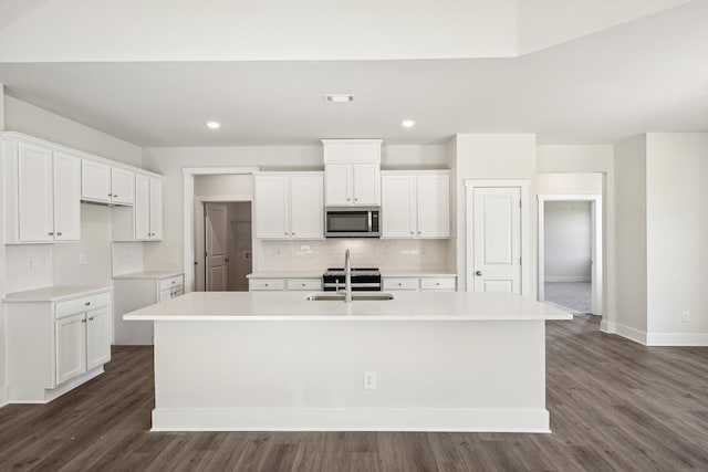 kitchen with sink, white cabinetry, backsplash, an island with sink, and dark hardwood / wood-style flooring