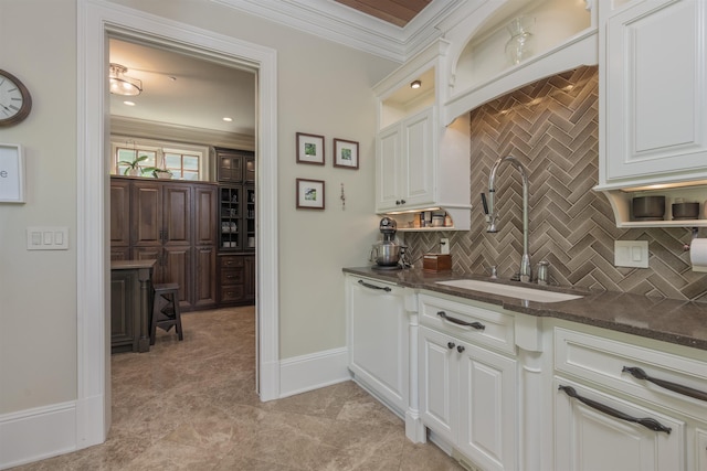 kitchen featuring sink, dark stone countertops, white cabinets, decorative backsplash, and ornamental molding