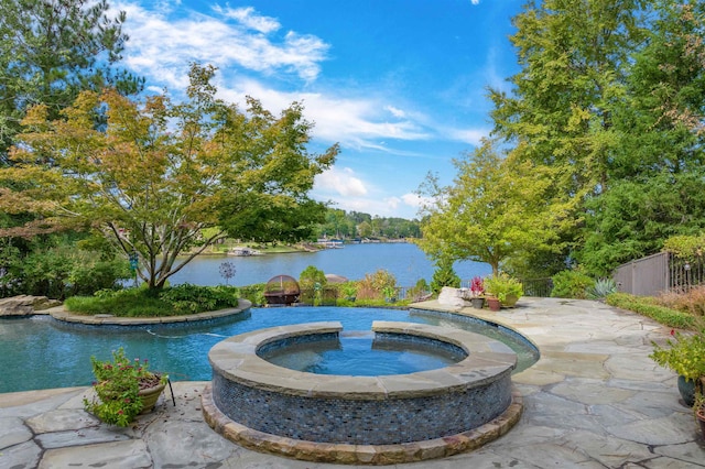 view of pool featuring an in ground hot tub, a water view, and a patio area