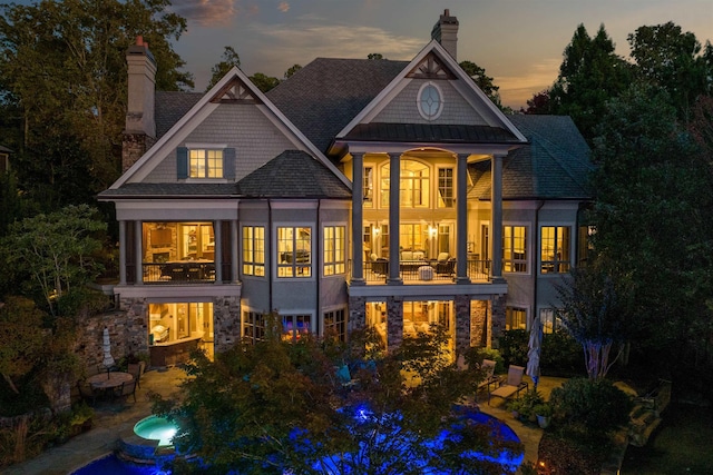 back house at dusk with a balcony