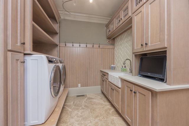 laundry room featuring cabinets, ornamental molding, washer and clothes dryer, and sink