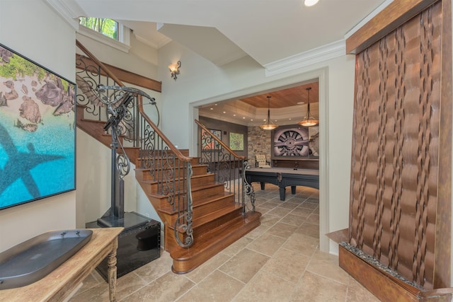 stairs with pool table, ornamental molding, and a raised ceiling