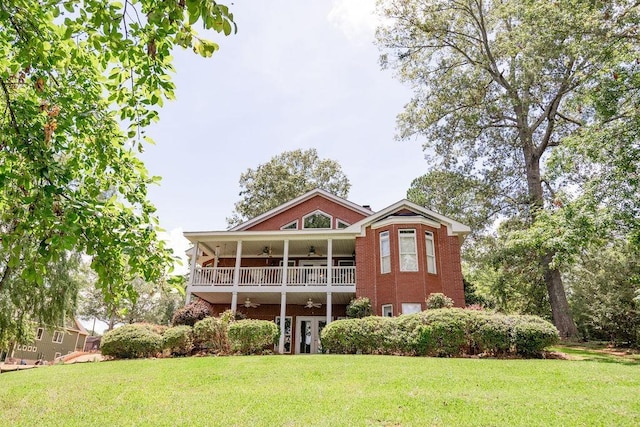 back of property featuring a lawn, a balcony, and ceiling fan