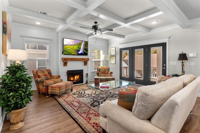 living room featuring ceiling fan, coffered ceiling, a fireplace, wood-type flooring, and beamed ceiling