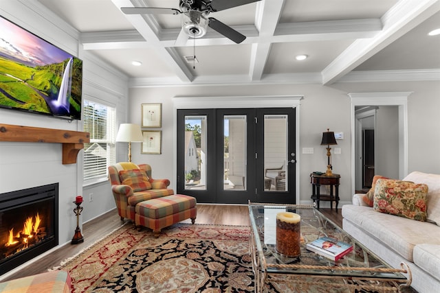 living room featuring coffered ceiling, wood-type flooring, ornamental molding, ceiling fan, and beam ceiling