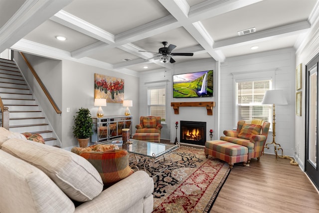 living room featuring a fireplace, beamed ceiling, ornamental molding, coffered ceiling, and light hardwood / wood-style floors