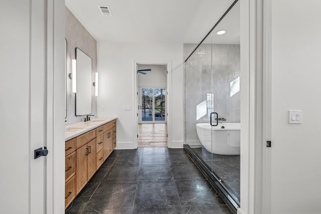 full bath featuring baseboards, double vanity, a freestanding tub, visible vents, and a sink