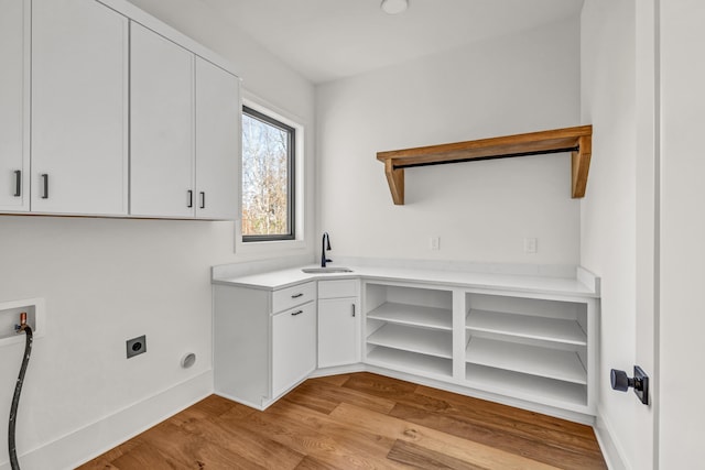 washroom with hookup for an electric dryer, cabinet space, a sink, light wood-style floors, and washer hookup