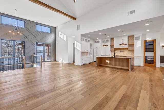 living area with light wood-type flooring, high vaulted ceiling, and visible vents