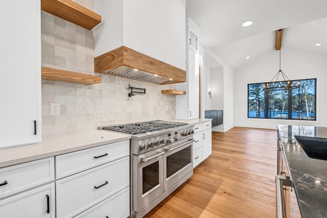 kitchen featuring pendant lighting, range with two ovens, white cabinets, light wood-style floors, and custom range hood