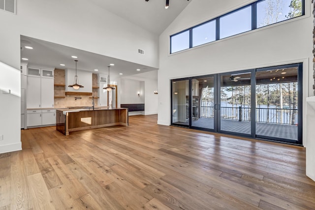 living area with light wood-type flooring, baseboards, visible vents, and ceiling fan