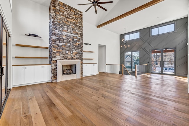 unfurnished living room featuring light wood-style floors, a stone fireplace, a ceiling fan, and high vaulted ceiling