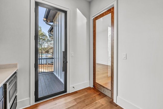 doorway with light wood-style flooring and baseboards