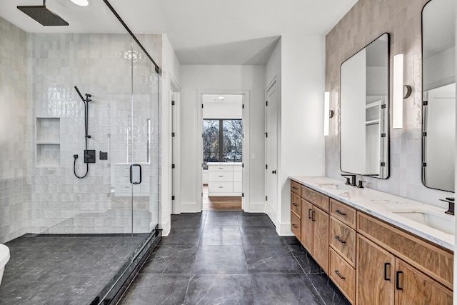 bathroom with double vanity, baseboards, a stall shower, and a sink