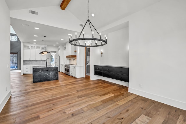 interior space with visible vents, beamed ceiling, light wood finished floors, and baseboards