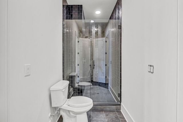 bathroom with baseboards, a shower stall, and toilet