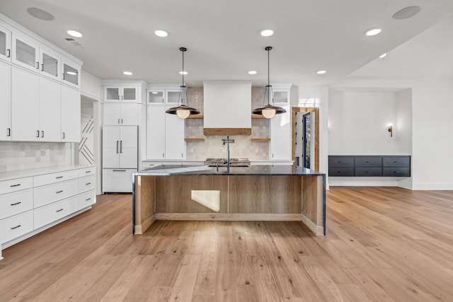 kitchen with a kitchen bar, glass insert cabinets, paneled built in refrigerator, hanging light fixtures, and white cabinetry